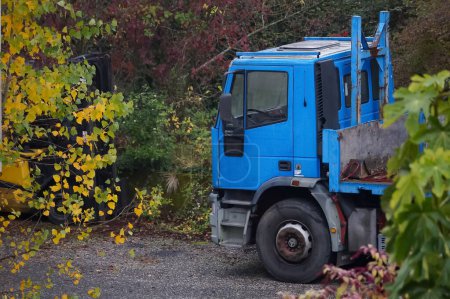 Foto de Albi, Francia - Dec. 2021 - Cabina azul y rueda delantera de un viejo camión de plataforma, un Eurotrakker 190E30 del fabricante italiano Iveco, con algunas piezas oxidadas, estacionado fuera de una fábrica industrial - Imagen libre de derechos