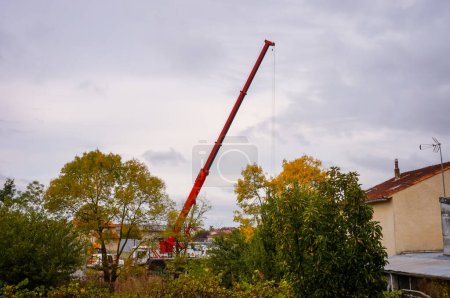 Photo for Albi, France - Oct. 2019 - The house arrest is being set up a new concrete enclosure wall in replacement of old barbec wire ; a Liebherr mobile crane with telescopic boom lifts prefabricated elements - Royalty Free Image