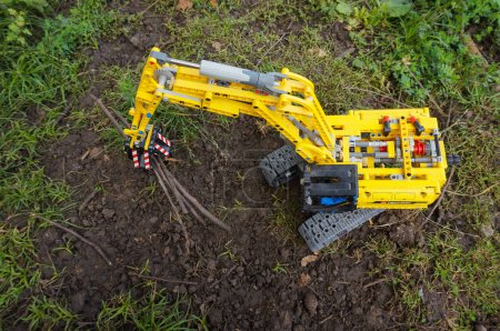 Foto de Excavadora de juguete amarillo en el jardín - Imagen libre de derechos