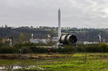 Foto de Toulouse, Francia - Marzo 2020 - Enormes tuberías industriales, vestigios de la explosión de la planta química AZF, frente a la chimenea de la fábrica del Grupo Ariane, donde se produce combustible para cohetes - Imagen libre de derechos