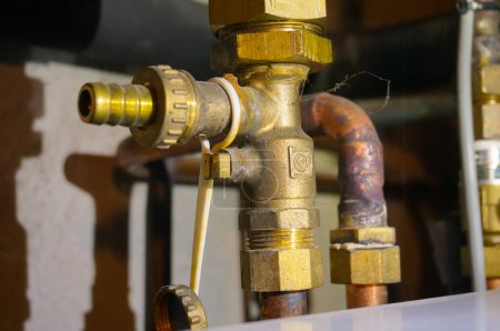 Photo for Detail of the tap of the brass and copper plumbing for the propane supply of a central heating system connected to town gas, installed in the basement of a house ; the copper pipe features weld traces - Royalty Free Image