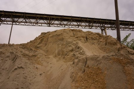 Téléchargez les photos : Une pile de sable surmontée d'une bande transporteuse soutenue par un cadre métallique, dans une usine de ciment dans le sud de la France - en image libre de droit