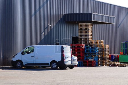 Photo for Albi, France - July 2022 - Side view on a white Renault Trafic delivery van, parked next to a stack of wooden pallets, in front of a storage unit, at the back of a modern E. Leclerc hypermarket - Royalty Free Image