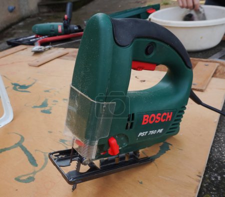 Photo for Tarn, France - May 2020 - Made-in-Switzerland electric jig saw produced by the renowned German manufacturer Bosch, equipped with a metal blade for wood cutting, in the outdoor atelier of an artisan - Royalty Free Image