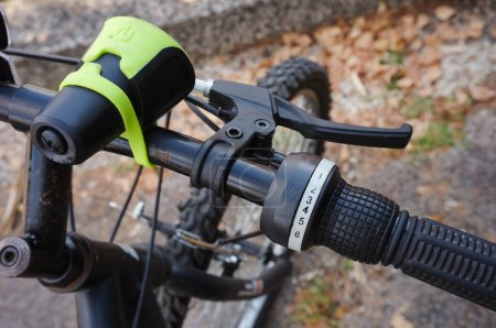 Foto de Detalle del manillar de aluminio negro de una bicicleta de montaña, con una vista más cercana de la palanca de freno y el cambio de marchas en el lado derecho, conectado a los cables, y el faro más cerca del eje - Imagen libre de derechos