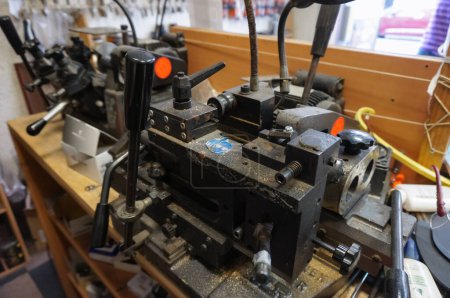 Foto de París, Francia - Sept. 2020 - Una máquina herramienta compleja en el taller de artesanos que trabajan en la industria de calzado o reparación y corte de llaves, con un cartel azul que aconseja el uso de protección ocular - Imagen libre de derechos