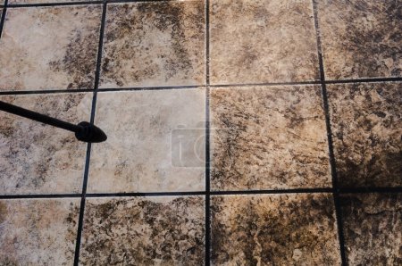 Téléchargez les photos : Entretien de la maison : comparaison entre les carreaux de sol extérieurs sales d'une terrasse et une tuile lavée et blanchie au moyen d'un nettoyant haute pression, avec quelques taches persistantes incrustées dans la pierre - en image libre de droit
