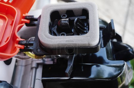 Foto de Componentes mecánicos de un nuevo cortador de cepillo de gasolina de diseño alemán: detalle del filtro de espuma, arrancador y palanca de estrangulamiento para el control de la entrada de aire en el carburador del motor térmico - Imagen libre de derechos