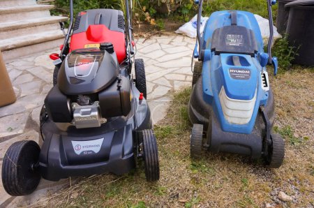 Photo for Tarn, France - May 2020 - A gas lawn mower motorized by the Japanese automaker Honda and distributed by Sterwins (Leroy Merlin) next to an electric one powered by the Korean manufacturer Hyundai - Royalty Free Image