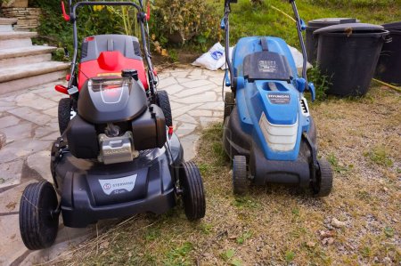 Photo for Tarn, France - May 2020 - A petrol lawn mower motorized by the Japanese automaker Honda and distributed by Sterwins (Leroy Merlin) next to an electric one powered by the Korean manufacturer Hyundai - Royalty Free Image