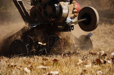 Photo for Aveyron, France - Aug. 2022 - A rotary tiller covered with dust in action in a dry, sandy soil ; this powerful model assembled in France features a two-stroke engine made in China, and six steel tines - Royalty Free Image