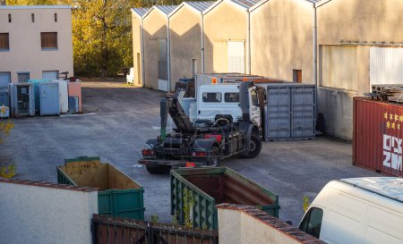 Foto de Tarn, Francia - Feb. 2021 - Un camión, con equipos de elevación del fabricante francés Dalby, maniobra a la inversa para recuperar un contenedor de basura, en el patio de un centro logístico - Imagen libre de derechos