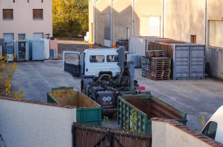 Téléchargez les photos : Tarn, France - Fév. 2021 - Un camion à porte ouverte, équipé d "équipements de levage du fabricant français Dalby, décharge une benne à ordures amovible dans la cour d'un centre de stockage - en image libre de droit