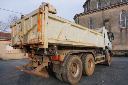 Photo for Villefranche d'Albigeois, France - Feb. 2021 - Rear view of a white, six-wheeled Renault tipper truck on a worksite, featuring the locking system of the tailgate of the dumper, which has traces of mud - Royalty Free Image