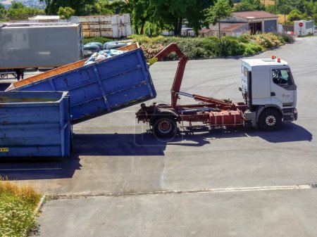 Foto de Albi, Francia - Julio 2016 - Camión volquete recuperando su contenedor extraíble con un brazo hidráulico, en el centro de recepción de residuos de Albi-Ranteil operado por la Comunidad Urbana de Grand Albigeois - Imagen libre de derechos
