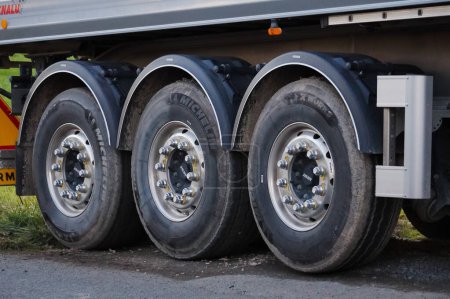 Foto de Salies, Francia - Dec. 2021 - Las tres ruedas traseras, algunas equipadas con neumáticos del fabricante francés Michelin, con tuercas que unen los ejes, sobre el volquete de un camión semirremolque - Imagen libre de derechos
