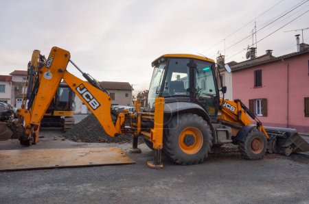 Foto de Tarn, France - Feb. 2021 - A yellow tractor from the British manufacturer JCB, parked on a construction site, featuring a front hydraulic loader and a rear-actor backhoe with an articulated boom - Imagen libre de derechos