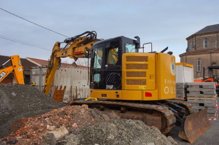 Téléchargez les photos : Tarn, France - Feb. 2021 - A yellow tractor from the British manufacturer JCB, parked on a construction site, featuring a front hydraulic loader and a rear-actor backhoe with an articulated boom - en image libre de droit