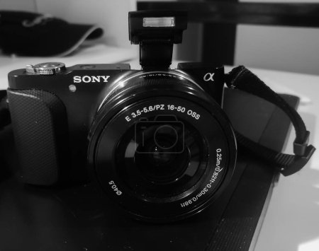 Téléchargez les photos : France, juillet 2019 - Photo noir et blanc d'un appareil photo hybride compact, Sony NEX 3 de la gamme Sony Alpha, avec flash déployé - en image libre de droit