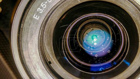 Téléchargez les photos : Tarn, France - Vers 2016 - Vue rapprochée de l'objectif optique d'un appareil photo Sony Alpha sans miroir conçu par Japanase, avec des reflets colorés sur le verre, des traces d'éclaboussures et quelques rayures - en image libre de droit