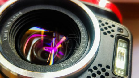 Téléchargez les photos : Tarn, France - Vers 2016 - Vue rapprochée d'un objectif Xacti HD d'un caméscope numérique Sanyo de conception japonaise, avec des reflets colorés sur le verre, des microphones stéréo et un flash intégré - en image libre de droit