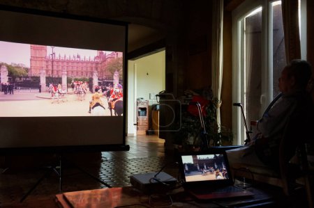 Téléchargez les photos : Tarn, France - Mai 2020 - Cinéma maison et temps libre dans la vie réelle : pendant le confinement du coronavirus, une famille française regarde une émission web télévisée diffusée sur un écran de projection dans le salon - en image libre de droit