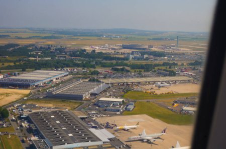 Photo for Roissy, France - June 2019 - Aerial view of a freight area, with cargo aircrafts in front of large warehouses served by semi-trailer trucks, in the huge airfield of Paris-Charles de Gaulle Airport - Royalty Free Image