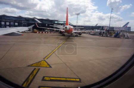 Foto de Roissy, Francia - Junio 2019 - Un avión de media distancia de la compañía aérea de bajo coste Easy Jet, abordando en una puerta terminal del aeropuerto París-Roissy Charles de Gaulle, visto desde una ventana de avión - Imagen libre de derechos