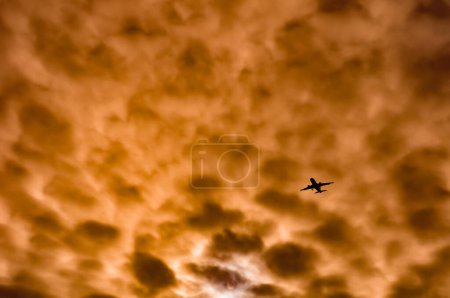 Photo for Airplane in flight with dramatic orange sky - Royalty Free Image
