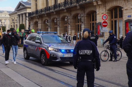 Foto de Reims, Francia - Marzo 2021 - Una oficial de policía y algunas de sus compañeras en bicicleta o a pie, rodeando un nuevo Peugeot 5008 de la Policía Nacional, en la calle de Vesle durante una manifestación - Imagen libre de derechos