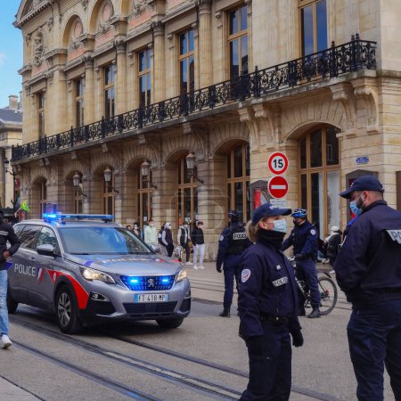 Foto de Reims, Francia - Marzo 2021 - Oficiales de policía femeninos y masculinos charlando frente a un nuevo Peugeot 5008 de la Policía Nacional, con luces azules encendidas, en intervención en la calle Rue de Vesle - Imagen libre de derechos