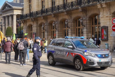 Foto de Reims, Francia - Marzo 2021 - El nuevo Peugeot 5008 de la Policía Nacional, con luces azules encendidas, y una oficial de policía de servicio en Rue de Vesle durante una manifestación de estudiantes - Imagen libre de derechos