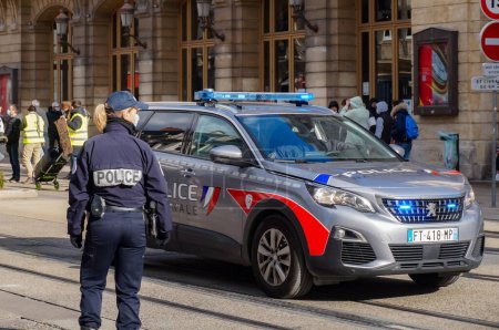 Téléchargez les photos : Reims, France - Mars 2021 - Une femme officier à côté de la toute nouvelle Peugeot 5008 de la "Police nationale", avec des feux clignotants bleus allumés, en intervention rue de Vesle lors d'une manifestation - en image libre de droit