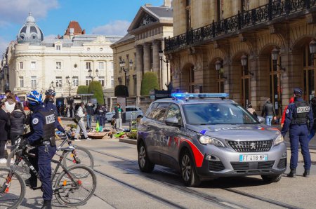 Téléchargez les photos : Reims, France - Mars 2021 - Des policiers à vélo, sur la place Myron Herrick, et une toute nouvelle Peugeot 5008 de la police nationale, avec des feux clignotants bleus allumés, sécurisant une manifestation rue de Vesle - en image libre de droit