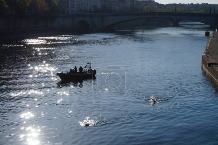 Foto de París, Francia - Abril 2021 - Un bote de goma de la Patrulla Náutica de la Prefectura de Policía navega por el río Sena, mientras dos buzos de la policía nadan río abajo por el puente de Pont d 'Arcole - Imagen libre de derechos