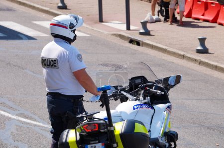 Téléchargez les photos : Albi, France - 21 août 2021 - Un motocycliste de la Police nationale, debout à côté de sa moto, surveille une manifestation contre la vaccination obligatoire pour les travailleurs de la santé et le laissez-passer sanitaire" - en image libre de droit