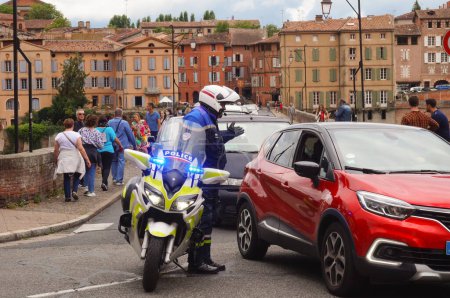 Photo for Albi, France - Aug. 7, 2021 - A motorcyclist of the French National Police on traffic duty reroutes drivers and inhabitants, while a rally against health restrictions is taking place in downtown - Royalty Free Image