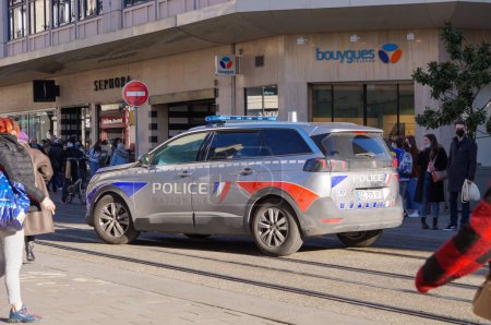Foto de Reims, Francia - Feb. 2022 - Un todoterreno Peugeot 5008 gris y marcado de la Policía Nacional, con luces azules encendidas, acompaña una manifestación en la Rue de Vesle, una de las calles principales del centro de la ciudad - Imagen libre de derechos