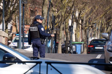 Photo for Toulouse, France - Feb. 2023 - A female police officer controls traffic on Marshall Leclerc Boulevard, while a demonstration against the government's pension reform blocks several streets downtown - Royalty Free Image