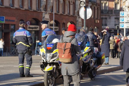 Foto de Toulouse, Francia - Feb. 2023 - Un grupo de tres oficiales armados de la Policía Municipal de la ciudad, vestidos con chalecos tácticos, patrullan en la Plaza Saint-Cyprien, en medio de protestas contra la reforma de las pensiones - Imagen libre de derechos
