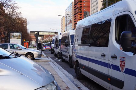 Photo for Toulouse, France - Jan. 2020 - Car traffic and motorcade of Renaul Master minibuses of the French National Police's riot units (CRS) at a stop light in Strasbourg Boulevard during social protests - Royalty Free Image
