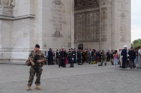 Foto de París, Francia - Julio 2019 - Oficiales franceses y extranjeros, funcionarios, veteranos de guerra y militares ordinarios en una ceremonia bajo el Arco del Triunfo, bajo la vigilancia de un soldado del Ejército francés - Imagen libre de derechos