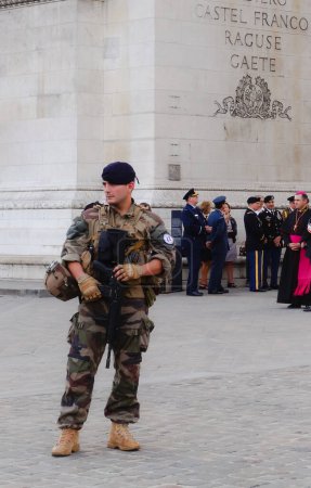 Foto de París, Francia - Julio 2019 - Oficiales franceses y extranjeros, funcionarios, veteranos de guerra y militares ordinarios en una ceremonia bajo el Arco del Triunfo, bajo la vigilancia de un soldado del Ejército francés - Imagen libre de derechos