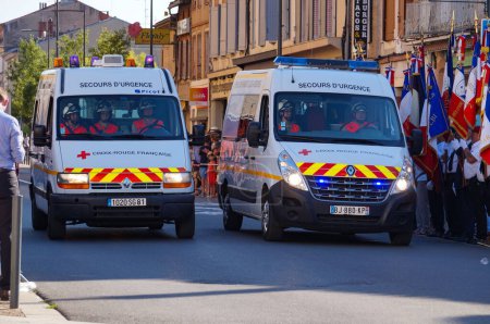 Téléchargez les photos : Albi, France - 14 juillet 2022 - Deux fourgonnettes Renault Sprinter blanches, véhicules d'urgence, de la Croix-Rouge française, défilant dans la rue au milieu des célébrations de la fête nationale - en image libre de droit