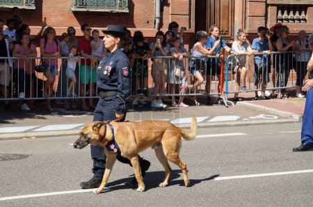 Foto de Toulouse, Francia - 14 de julio de 2023 - Una mujer que maneja perros con la Gendarmería (policía militar francesa) con un pastor belga, en el desfile del Día Nacional; ambas llevan medallas militares por su servicio - Imagen libre de derechos