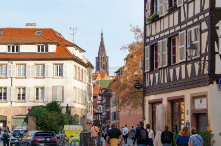 Foto de Estrasburgo, Francia - Nov. 2022 - Vista al fondo del campanario de la Catedral de Notre-Dame desde la calle Bain-aux-Plantes y la plaza Grimmeissen, en el centro histórico turístico y lleno de gente - Imagen libre de derechos