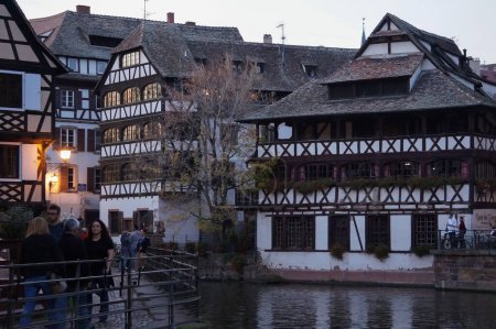 Foto de Estrasburgo, Francia - Nov. 2022 - Vista nocturna con típicas casas tradicionales de entramado de madera en el pintoresco barrio de Petite France, en el río Ill, en el centro histórico de la ciudad - Imagen libre de derechos