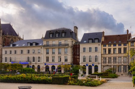 Foto de Troyes, Francia - Sept. 2020 - Elegantes edificios tradicionales de la ciudad, con arcadas que albergan tiendas y sucursales bancarias, junto a la Place de la Libration, una hermosa plaza ajardinada y verde en el centro de la ciudad - Imagen libre de derechos