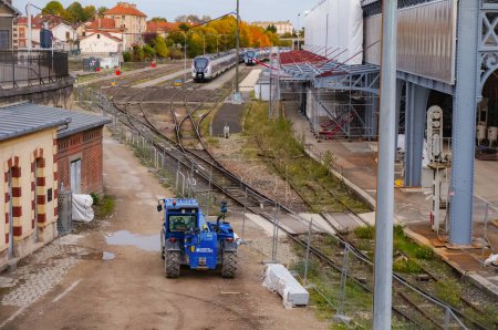 Photo for Troyes, France - Oct. 2020 - Storage tracks (sidings) behind the city's railway station, with Alstom Regiolis TER (Regional Express Trains) in the background, and a telehandler in the forefront - Royalty Free Image