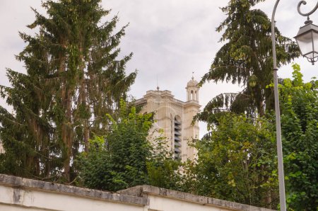 Foto de En parte escondido detrás de los árboles de un jardín, la parte superior del campanario renacentista de la Catedral de Saint-Pierre-et-Saint-Paul, un hito gótico que domina la ciudad de Troyes, en Francia - Imagen libre de derechos